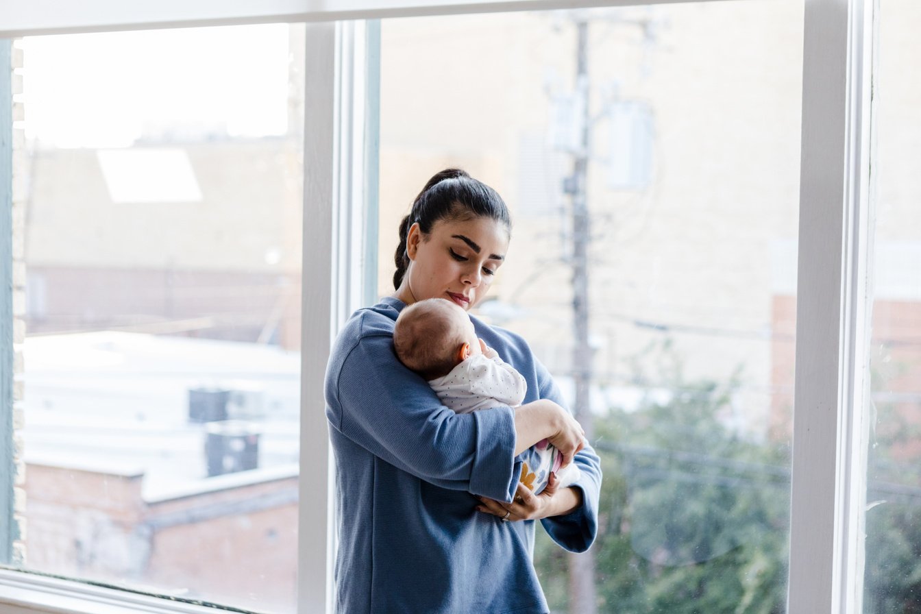 Nanny stands and holds onto young child