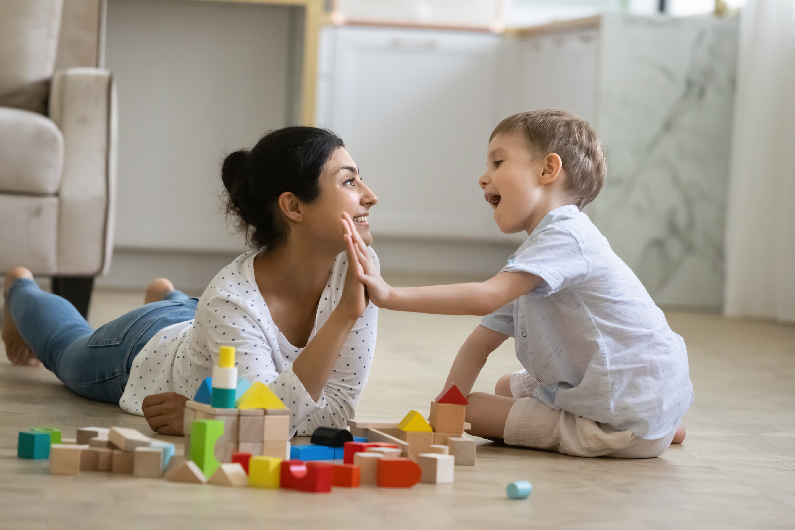 Happy nanny giving high five praise to excited preschool kid